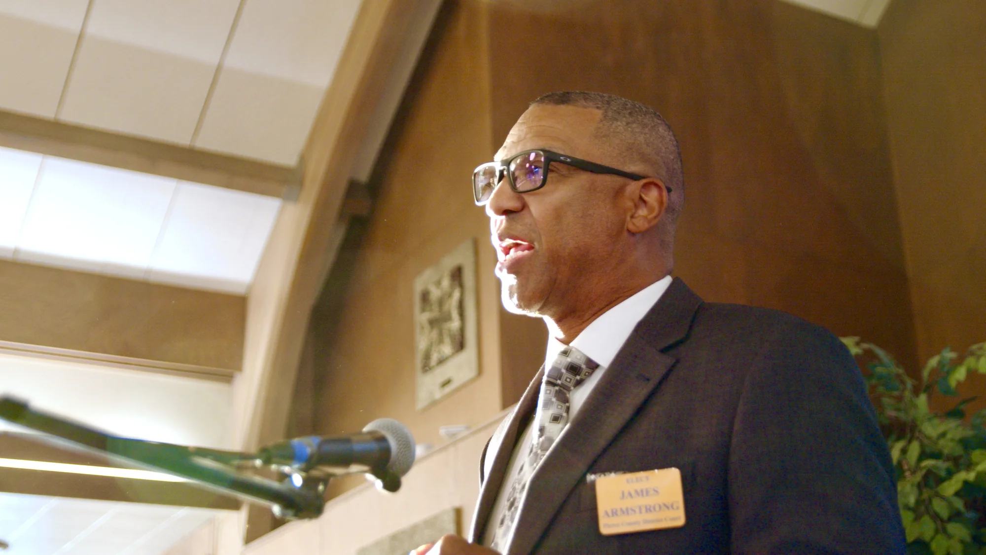 James Armstrong addressing a community gathering at a microphone