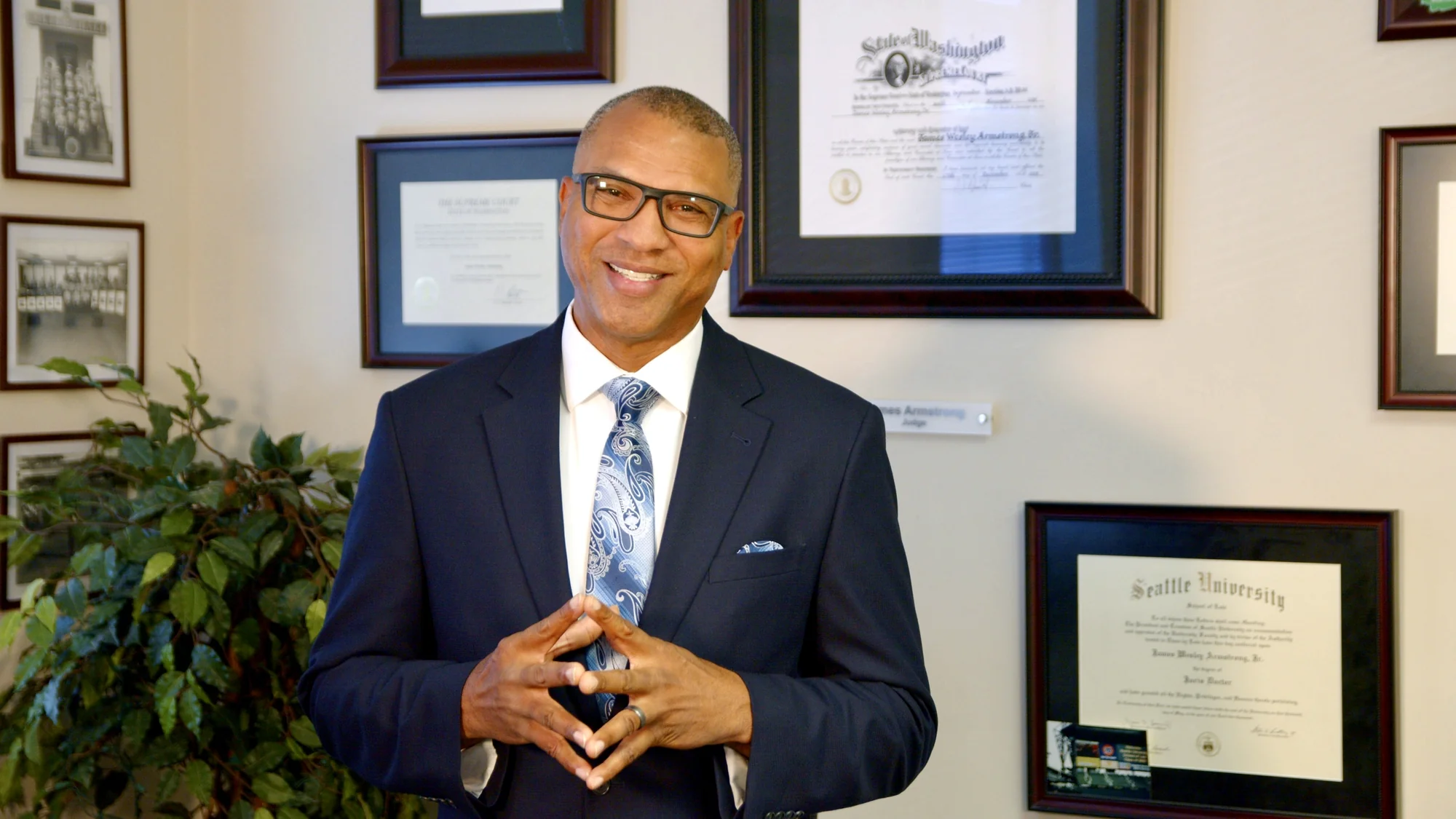 James Armstrong speaking in his office with framed credentials behind him