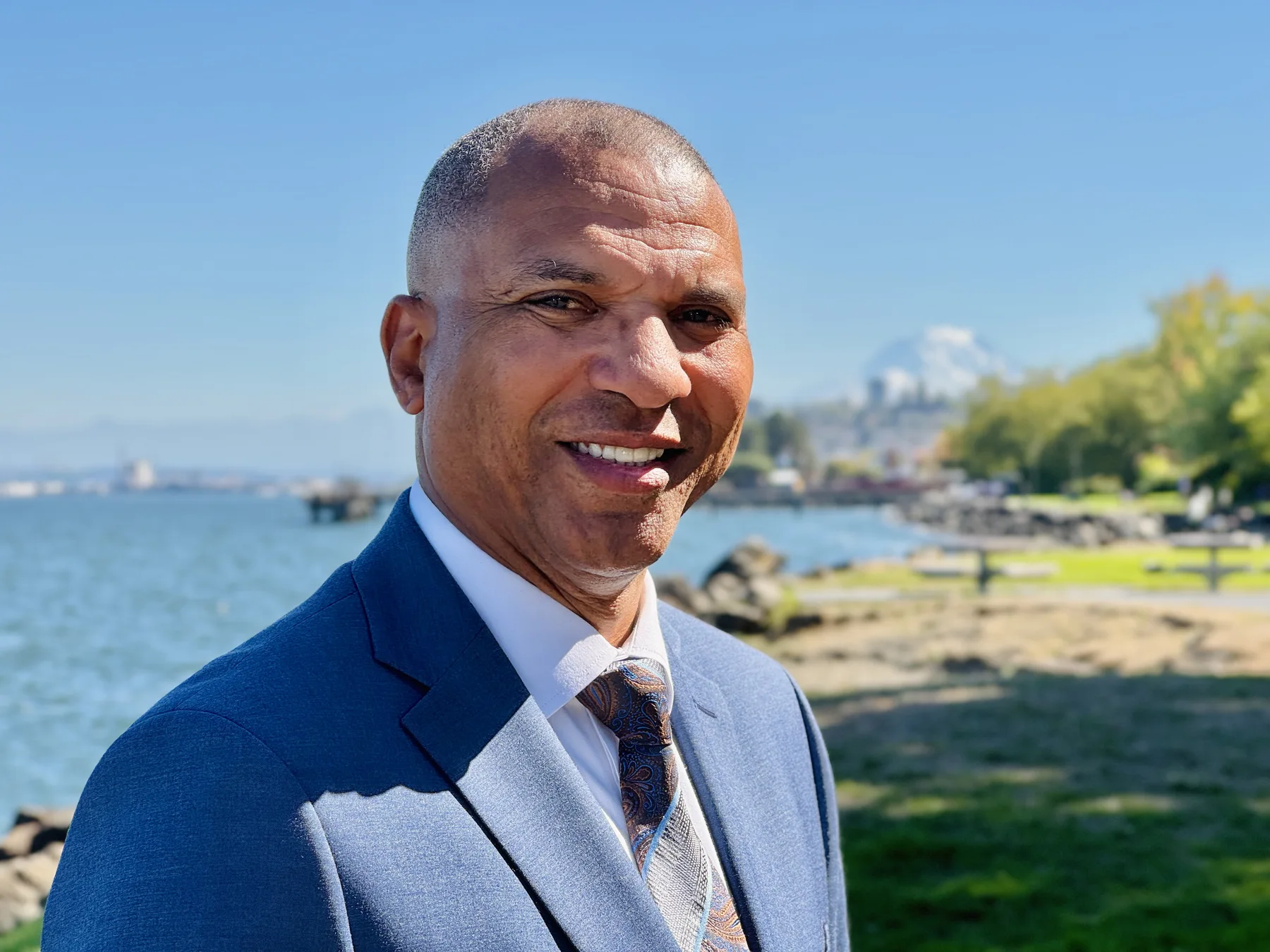 James Armstrong smiling beside the waterfront in a blue suit